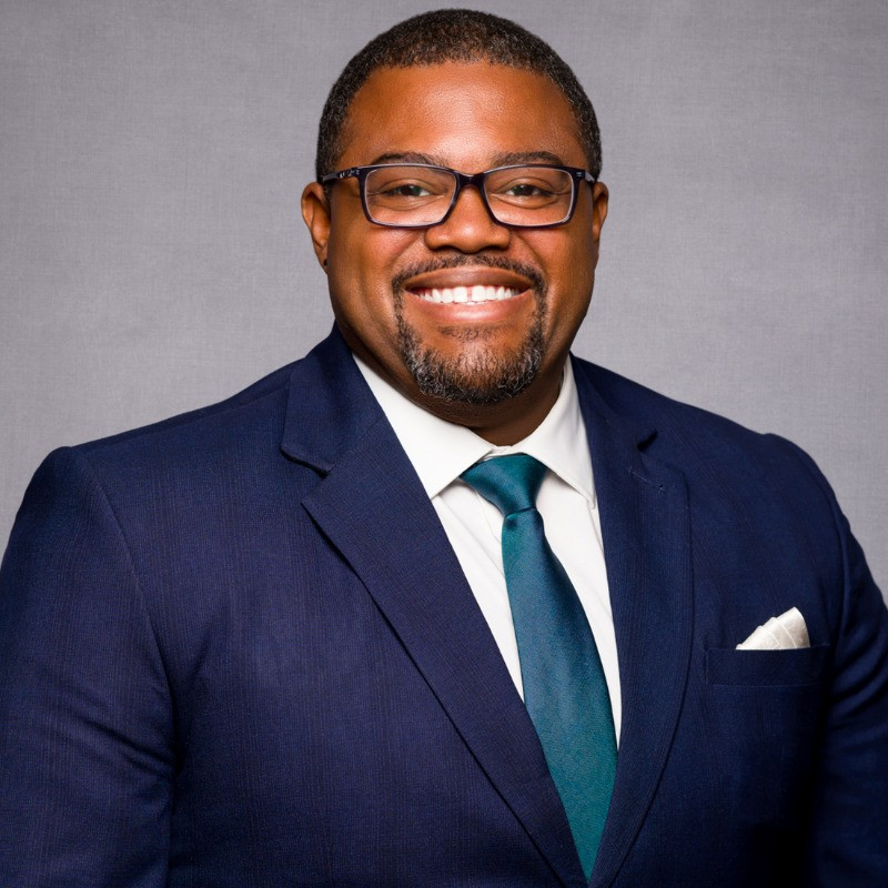 Bert_Dumas seen in a dark blur color suit and a bright smile on his face